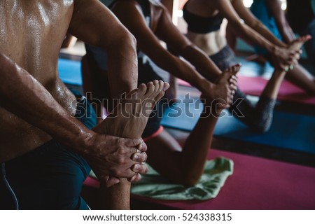 Men and women practicing yoga and meditation during yoga retreat vacation in studio Royalty-Free Stock Photo #524338315