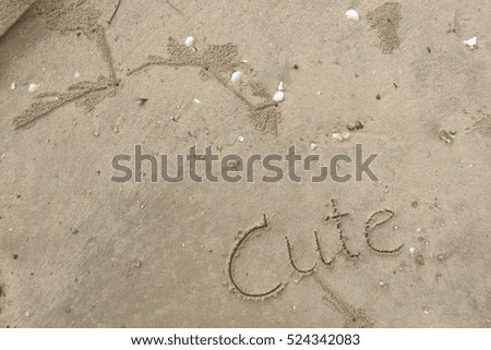 written words "Cute" on sand of beach