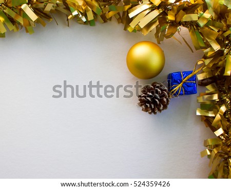 Gold Christmas ornament flat composition on white board. Golden ribbon. Gold fir tree ball. Blue wrapped gift. Lightened photo background with Christmas decor and present. Christmas banner template