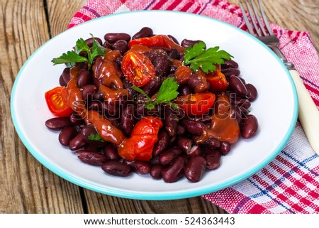 Salad with cherry tomatoes and red beans in spicy tomato sauce. Studio Photo