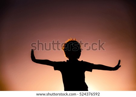 Silhouette of little boy play at sunset sky