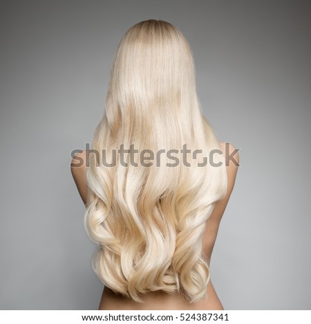 Portrait Of Beautiful Young Blond Woman With Long Wavy Hair. Back view Royalty-Free Stock Photo #524387341