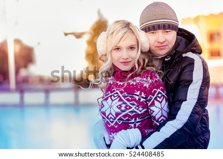 cute girl is going skate outdoors.girl in winter clothes skating on ice rink.Young woman skating on ice with figure skates.portrait girl.A loving couple skates. Love. Boy and girl hugging.