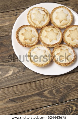 A plate full of freshly baked mince pies on a rustic wooden dining table background with blank space below