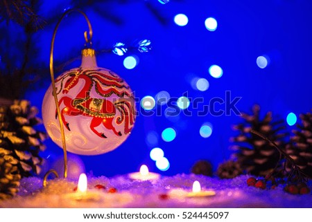 Christmas card with Christmas toy with painted red horse, on blue background with bokeh for your greetings