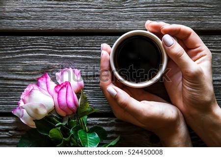 woman holding hot cup of coffee on a wooden background. Morning, drink, break