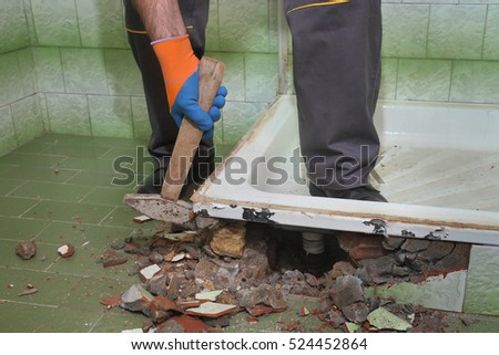 Worker remove, demolish old bathtub and tiles with hammer in a bathroom