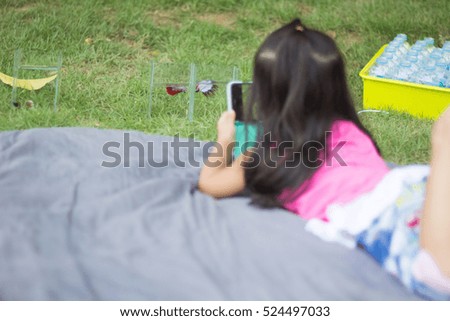 a girl use moblie phone taking photo of betta fish on the grass field ground floor.