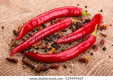The pods of red hot pepper, chili peperoncini and peas on burlap background