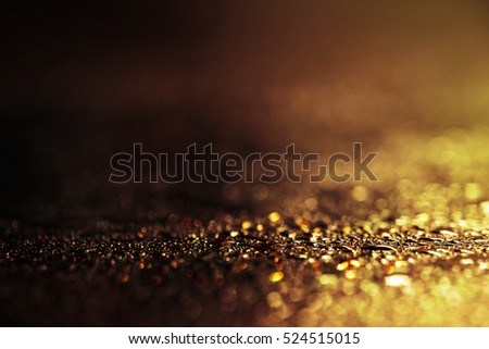 Abstract golden and brown background with shiny brilliant water drops, dew or rain on the glass with round bokeh.