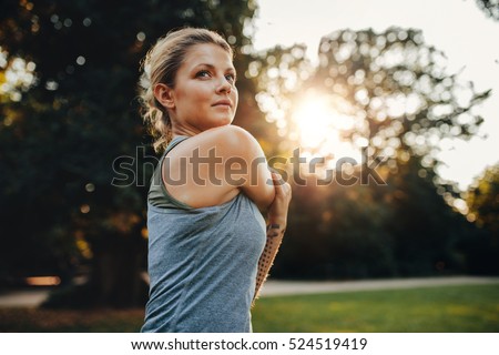 Portrait of beautiful young woman exercising in the park. Caucasian female fitness model working out in the morning. Royalty-Free Stock Photo #524519419