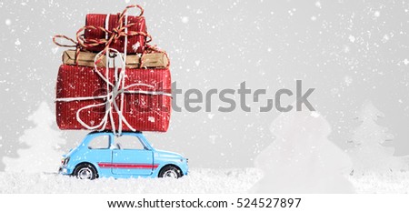 Blue retro toy car delivering Christmas or New Year gifts on gray background Royalty-Free Stock Photo #524527897