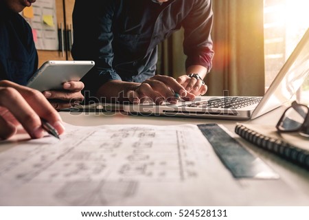 Two colleagues discussing data working and tablet, laptop with on on architectural project at construction site at desk in office Royalty-Free Stock Photo #524528131