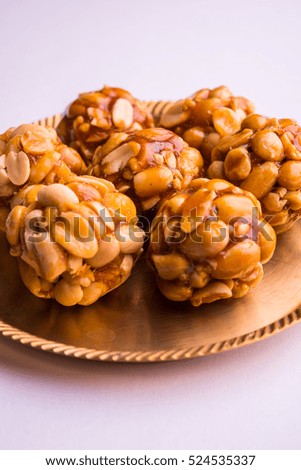 Healthy and sweet groundnut or peanut and Jaggery Laddoo, served in a brass plate isolated over white background. selective focus