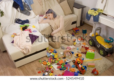 Mother sitting on the couch. Mom tired to tidy up the house. Child scattered toys. Children's room. Mess in the house Royalty-Free Stock Photo #524549410