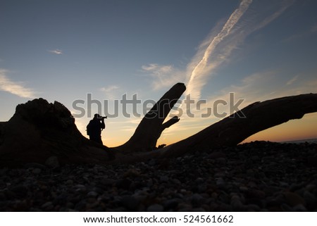 photographer at sunrise on the beach with a big snag