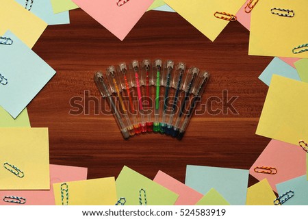Stationery, pens, paper clips, stickers lying on a wooden table