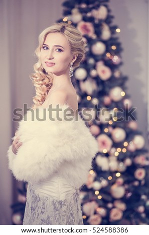 Beautiful blonde bride in a wedding dress on the background of the Christmas tree in his bedroom, wedding morning