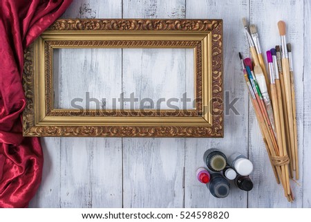 Old Framing frame lies on a white board next to the bottles of paint and brushes