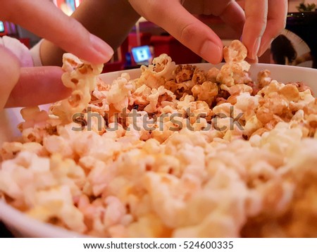 Sharing and eating popcorn when you watch movie at the theater Royalty-Free Stock Photo #524600335