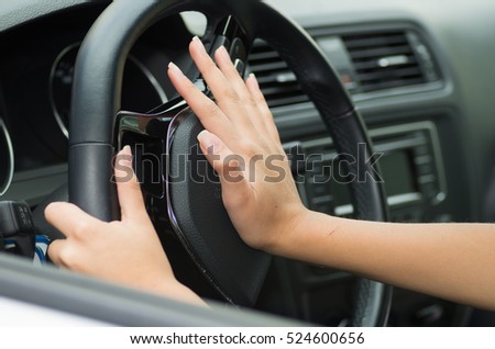 Closeup inside vehicle of hand pushing on steering wheel honking horn, black interior background, female driver concept Royalty-Free Stock Photo #524600656