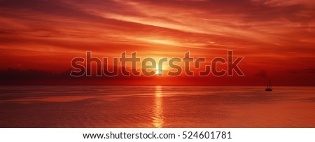 Beautiful colorful sunrise at the sea with dramatic clouds and sun shining Royalty-Free Stock Photo #524601781