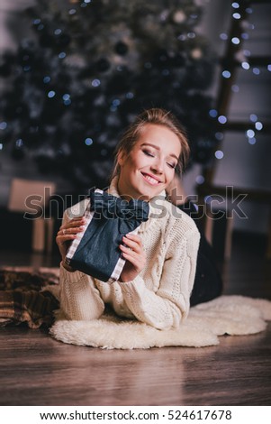 Beautiful young woman posing under Christmas tree in a holiday interior