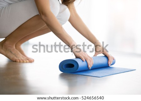 Close up shot of female hands unrolling yoga mat in a modern apartment, preparing for practice in class or at home. Yoga studio etiquette. Healthy lifestyle concept