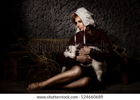 Beautiful country girl with a small goat in her hands