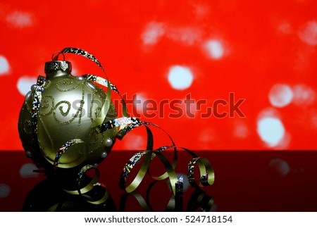 Christmas and New Year`s gold ball decorations with colorful ribbons on a black mirror reflection surface and red bokeh lights background.  Blank card template with copyspace for congratulations text.