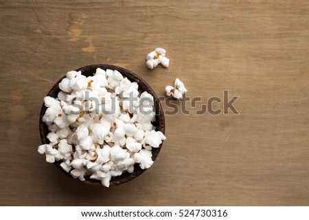 A bowl of pop corn from above with a wooden background.