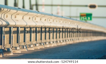 Guard rail or guardrail, sometimes referred to as guide rail or railing, is a system designed to keep people or vehicles from straying into dangerous or off-limits areas. Royalty-Free Stock Photo #524749114
