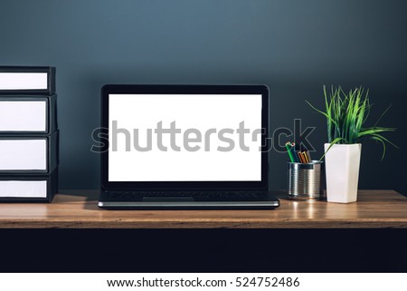Laptop computer with blank screen as copy space placed on office desktop in dark interior. Royalty-Free Stock Photo #524752486