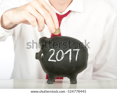 businessman putting money on a piggy bank with a year 2017 drawing Royalty-Free Stock Photo #524778445