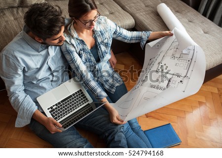 Young couple examining blueprints of they new house.Moving house concept. Royalty-Free Stock Photo #524794168
