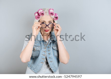 Bespectacled senior woman touching her glasses.