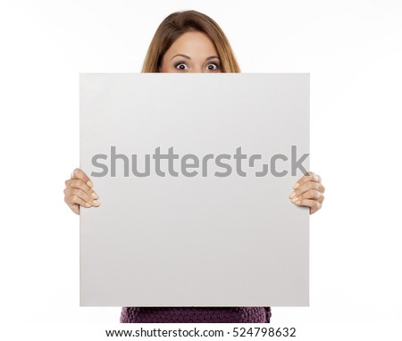 young beautiful woman peeking behind blank board for advertising