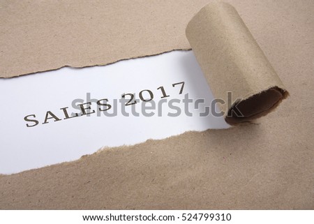 Torn brown paper on white surface with "sales 2017" words.