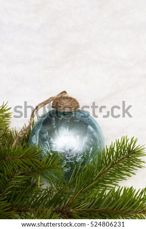 The christmas toy and tree branches. Blue glass ball is on the light background. 