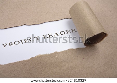 Torn brown paper on white surface with "project leader" word.
