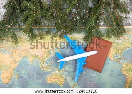 Christmas concept - travel. Fir branches with snow, maps, passport and toy airplane Royalty-Free Stock Photo #524813110