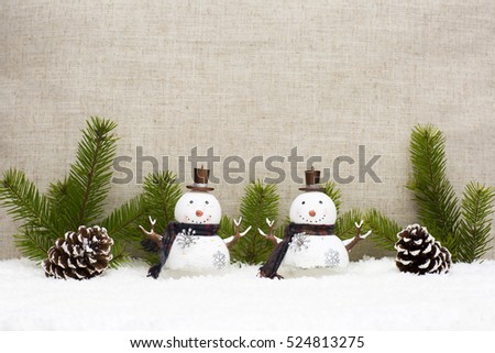 Christmas still life has  pine cones and the snowman. Light background has tree branches and linen fabric.  