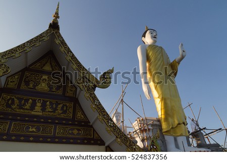 The Roof of Thai Church and The Buddha Stand Statue Under Construction with Blue Sky. (This picture is taken in a public area and be permitted to take picture for sale)