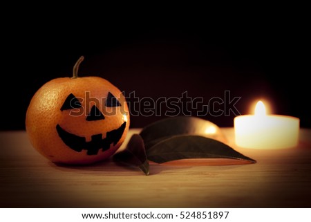 Tangerine - Halloween pumpkin with candle and leaves on a dark background. Still life picture taken in studio.