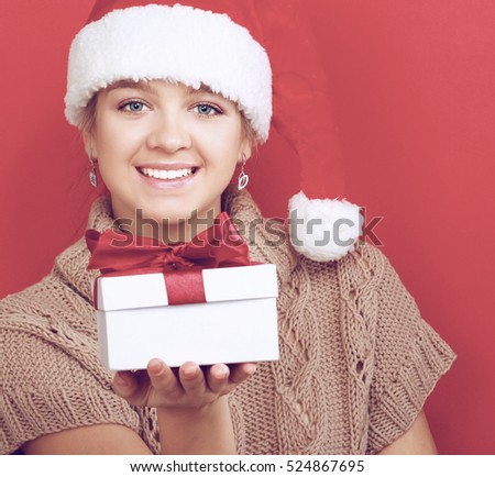 Santa girl holding Christmas gift on red background