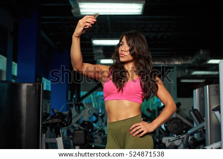 Sporty girl doing selfie at gym after workout. Young latina girl with smartphone 