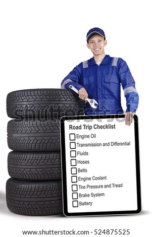Picture of a male mechanic holding wrench and board with road trip tips while standing near tires, isolated on the white background