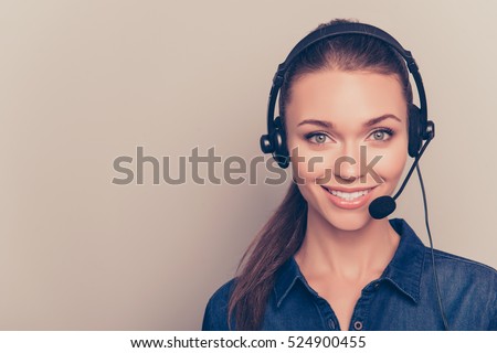 Beautiful consultant of call center in headphones on gray background. Royalty-Free Stock Photo #524900455