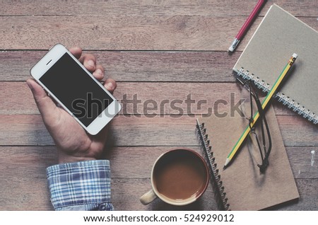 Office stuff and it gadgets display on top view business desk with copy space at text of picture. Creative table, modern project. Business man is hand working smartphone. Vintage tone filter effects. 