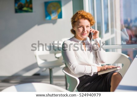 Businesswoman discussing burning problems and issues with partners over mobile phone. Red haired lady smiling and looking at window.